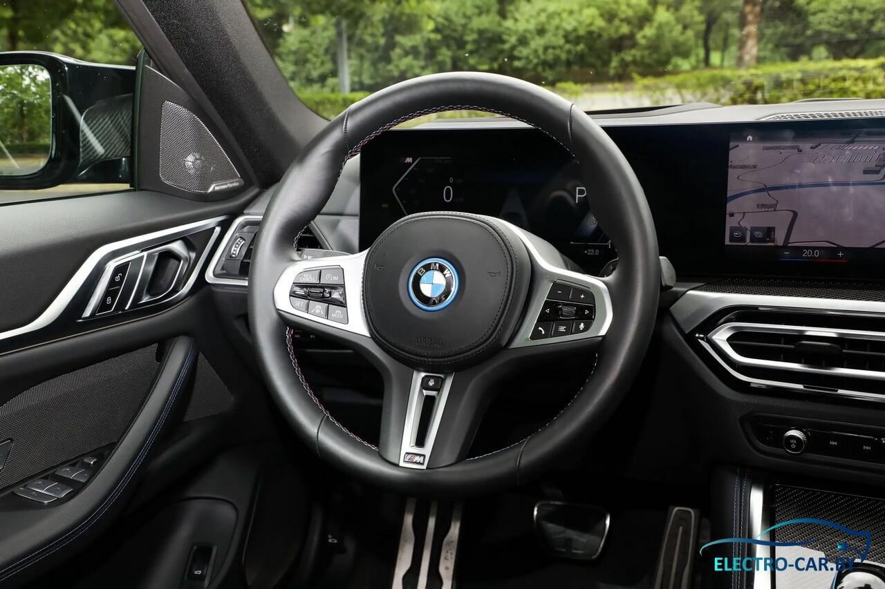 Интерьер электромобиля BMW i4, приборная панель и рулевое колесо.